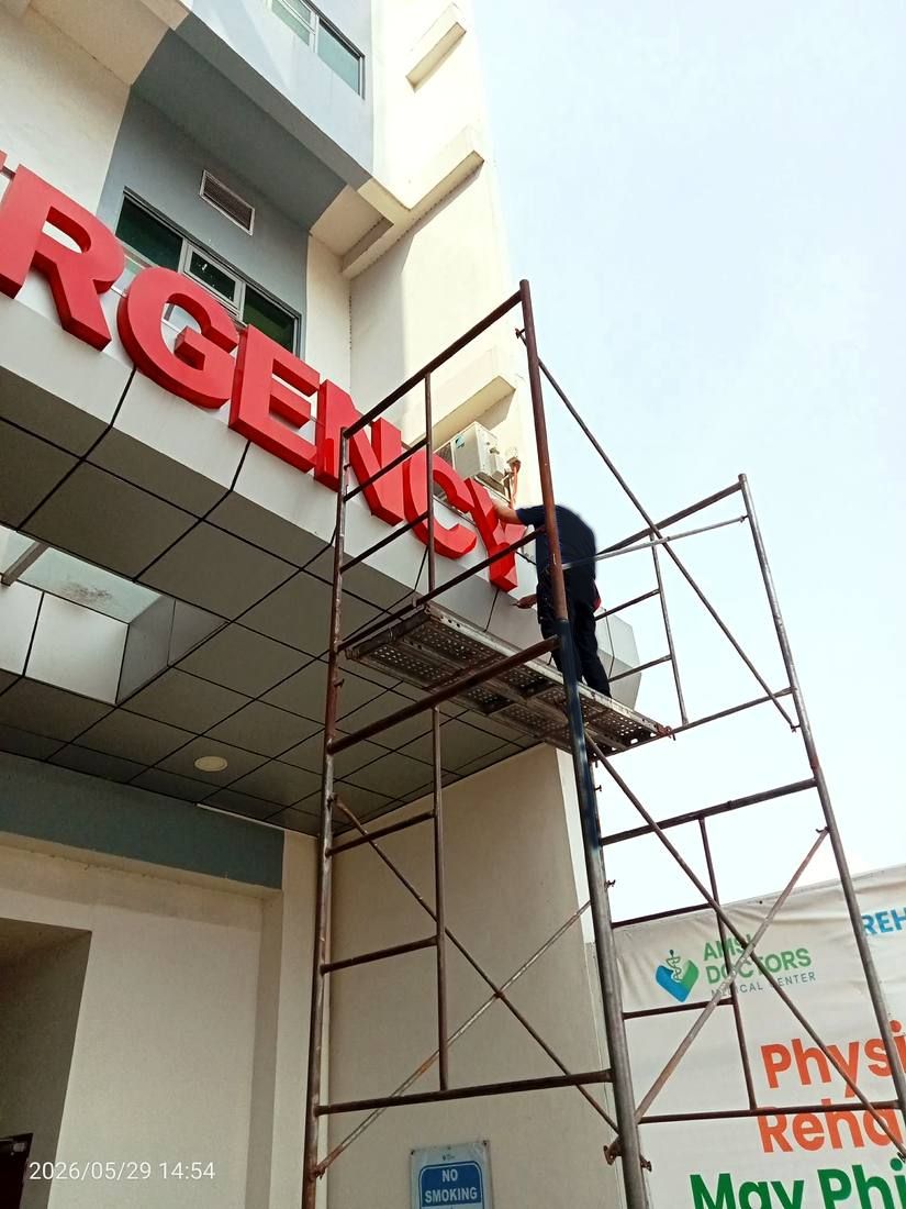 Technician repairing hospital emergency sign on scaffolding